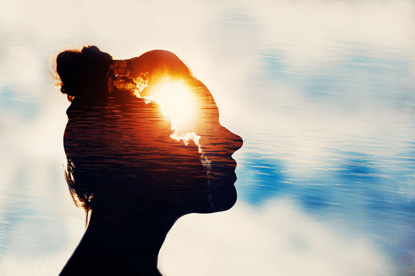 Woman in front of blue sky with clouds shown in her mind.