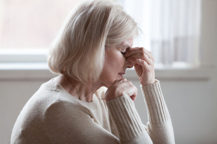 Fatigued older woman faces anxiety.