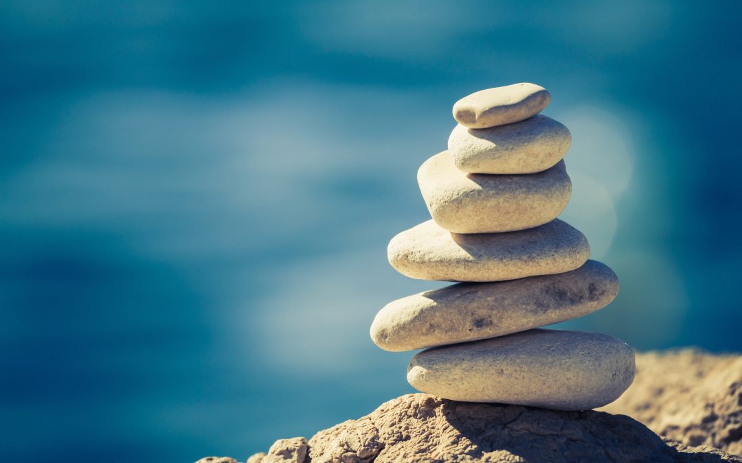 White pebbles stacked and carefully balanced over a blue sea