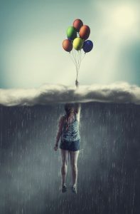 Woman flying with balloons through a rainy cloud to the sunny sky